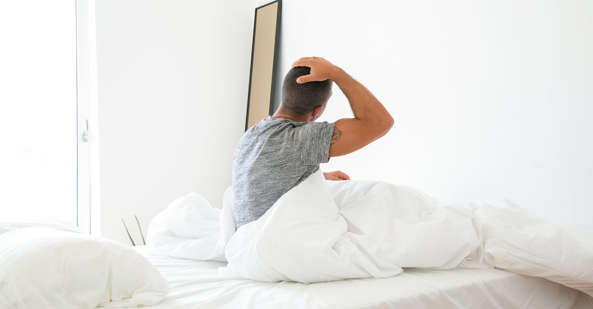 A man stretches in bed during a bright morning, starting his day.